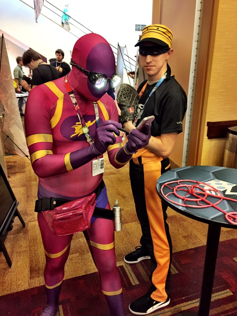 The Bottom of the 9th digital app released at Gen Con, and here we see Guise and Setback, two stars of the Sentinels of the 9th expansion pack, drumming up business at the GTG costume contest.